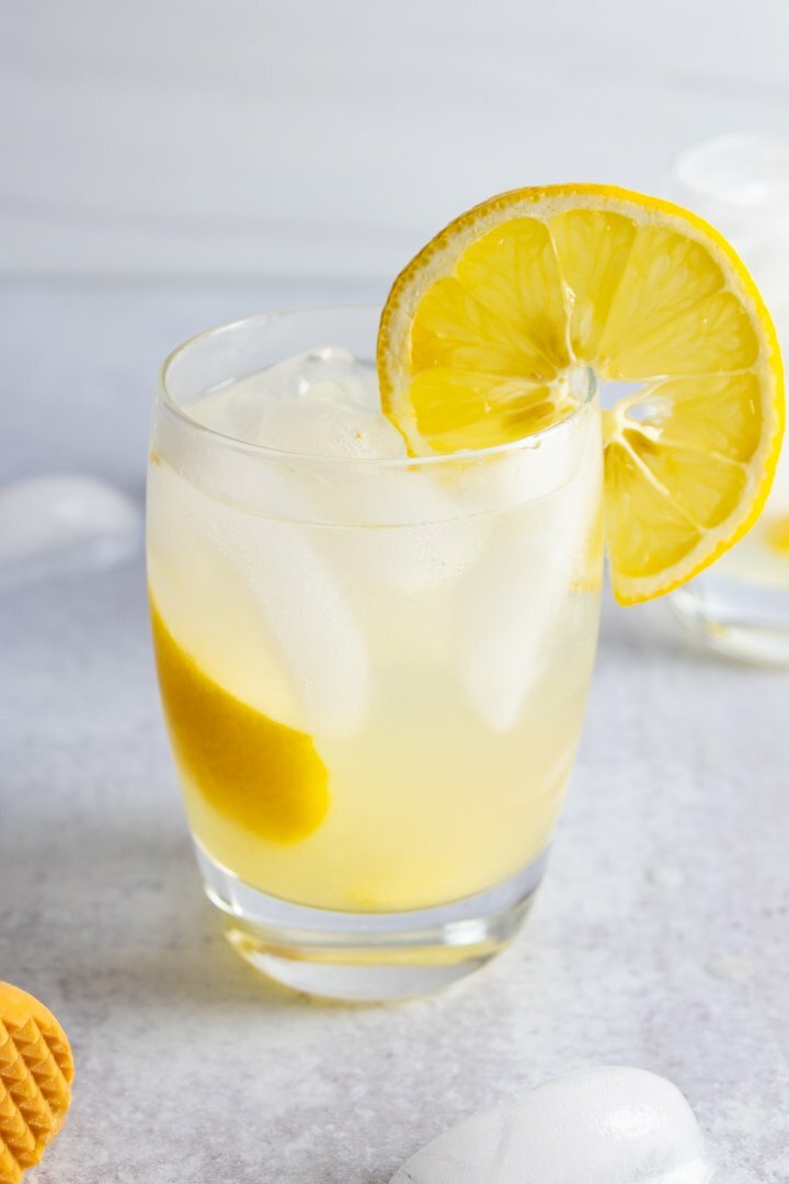 AIP Lemon Ginger Spritzer mocktail in a small glass with a lemon.