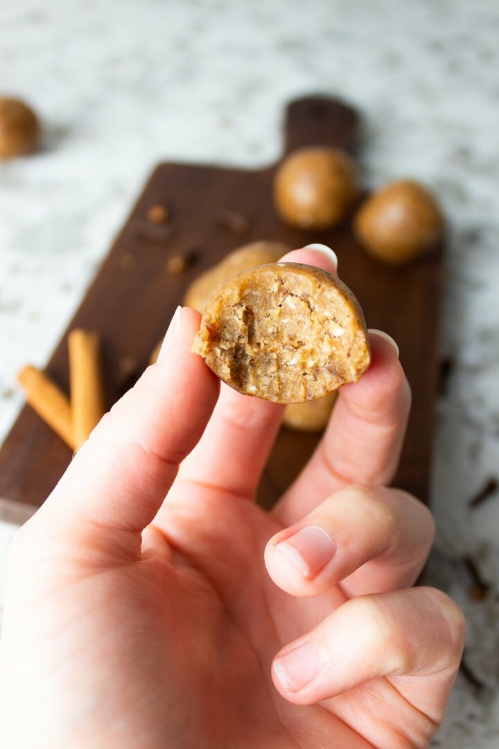 A hand holding a Chai Collagen Bliss Ball with a bite taken out of it.