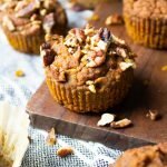 Close up of AIP Pumpkin Muffins on a striped kitchen towel with a wood serving board.