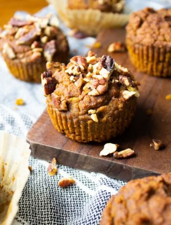 Close up of AIP Pumpkin Muffins on a striped kitchen towel with a wood serving board.