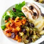 45º angle view of Paleo Autumn Harvest Bowls in white bowls with a plaid kitchen towel.