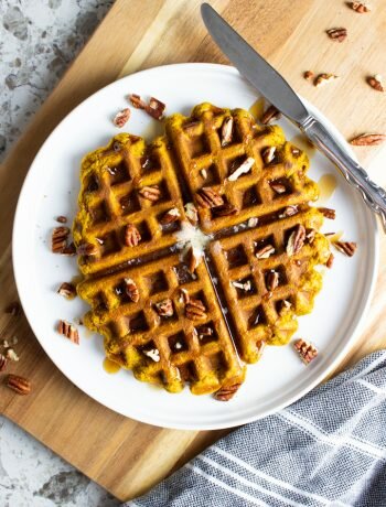 Overhead shot of AIP Pumpkin Waffles on a white plate with a silver knife.