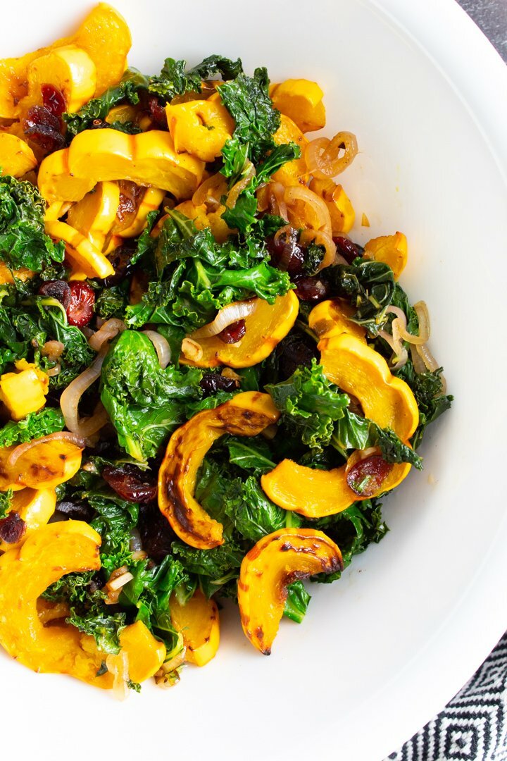 Top view of Warm Kale Salad with Roasted Delicata Squash in a white bowl.