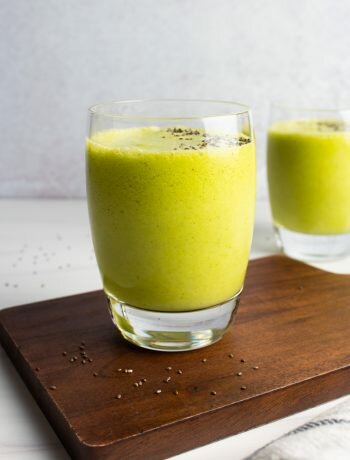 Mango Matcha Smoothies on a wood serving board with a grey background.