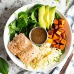 Top view of Paleo Salmon Power Bowl with sweet potatoes, cauliflower rice, spinach, avocado, salmon and maple-balsamic dressing.