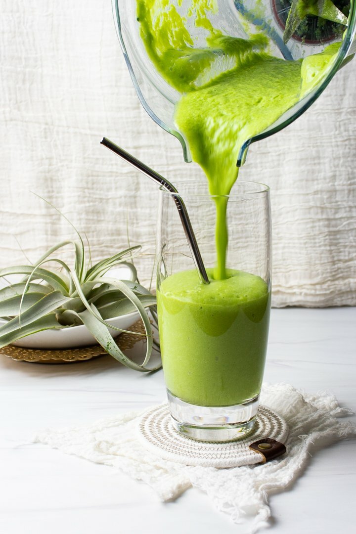 Mango Pineapple Green Smoothie pouring from a blender into a tall glass.